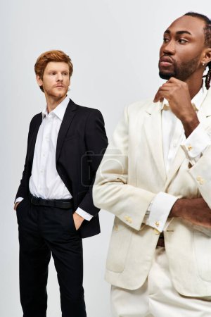 Foto de Dos hombres multiculturales en trajes elegantes de pie lado a lado. - Imagen libre de derechos