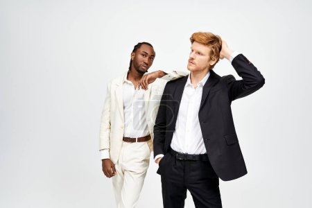 Dos guapos hombres multiculturales en trajes elegantes posando juntos.