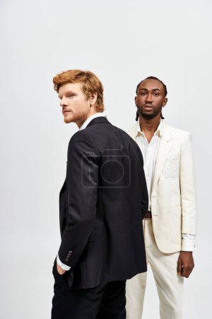 Foto de Dos elegantes hombres multiculturales en trajes de pie lado a lado. - Imagen libre de derechos