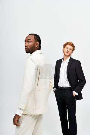 Zwei gutaussehende Männer, einer multikulturell, stehen elegant im Anzug.