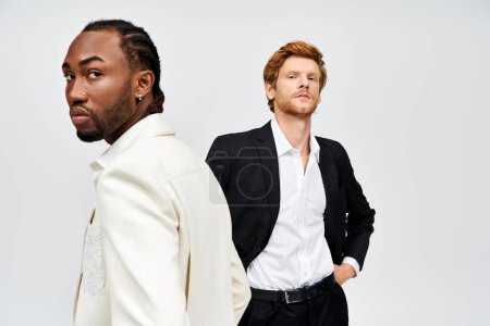 Two handsome, multicultural men in elegant suits posing together.