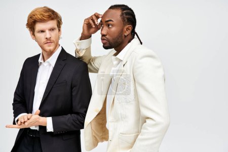 Téléchargez les photos : Deux beaux hommes multiculturels en costumes élégants debout ensemble. - en image libre de droit