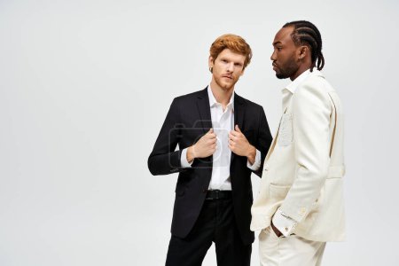 Téléchargez les photos : Deux beaux hommes multiculturels en costumes élégants se tiennent côte à côte. - en image libre de droit