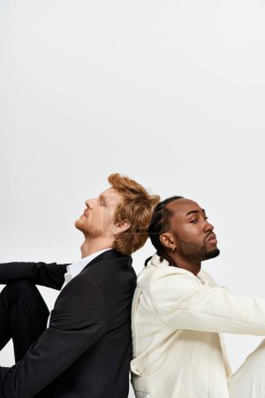 Téléchargez les photos : Deux beaux hommes multiculturels dans le style élégant dapper, assis à côté de l'autre. - en image libre de droit