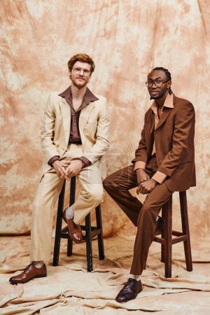 Téléchargez les photos : Deux hommes multiculturels en costumes élégants s'assoient étroitement ensemble. - en image libre de droit