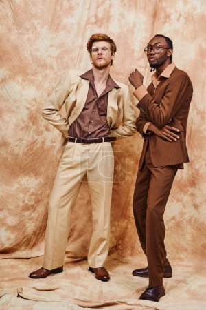 Téléchargez les photos : Beaux hommes multiculturels dans le style élégant dapper debout ensemble devant une toile de fond. - en image libre de droit