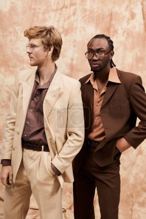 Foto de Dos hombres multiculturales en elegante estilo elegante están uno al lado del otro frente a una pared. - Imagen libre de derechos