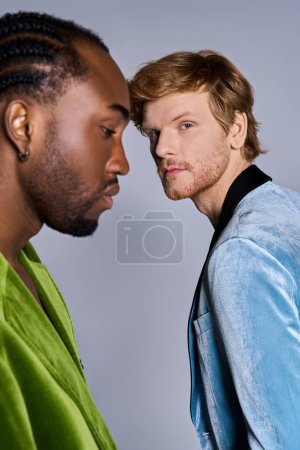 Téléchargez les photos : Deux hommes multiculturels en tenue de dapper debout ensemble, établissant un contact visuel. - en image libre de droit