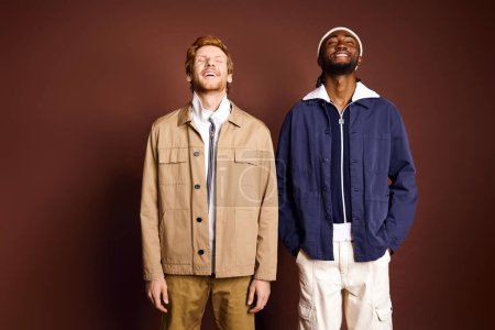Foto de Dos hombres de moda están junto a una pared marrón. - Imagen libre de derechos