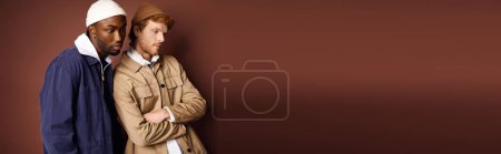 Téléchargez les photos : Des hommes multiculturels élégants posent devant un mur brun rustique. - en image libre de droit