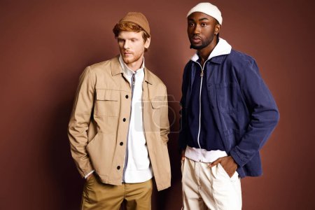 Zwei stylische multikulturelle Männer stehen vor einer braunen Wand.