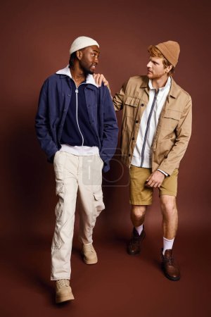 Zwei stylische junge Männer unterschiedlicher Herkunft posieren gemeinsam.