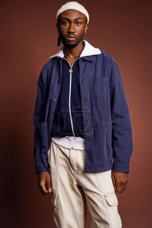 Ein hübscher junger afroamerikanischer Mann in blauer Jacke und brauner Hose.