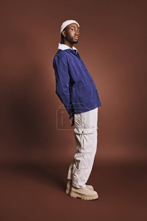 Un joven afroamericano guapo con chaqueta azul y pantalones blancos.