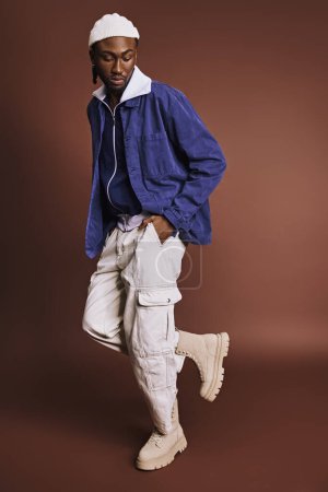 A handsome young African American man wearing a blue jacket and white pants.