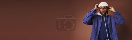 Photo for A handsome young African American man wearing a blue jacket and white hat. - Royalty Free Image