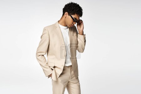 Handsome African American man wearing beige suit and stylish sunglasses.