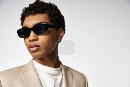 Stylish young man in tan suit and sunglasses.