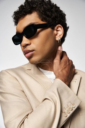 Hombre afroamericano guapo con gafas de sol elegantes y traje de bronceado.