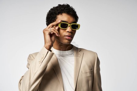 Stylish African American man in tan suit and yellow sunglasses.