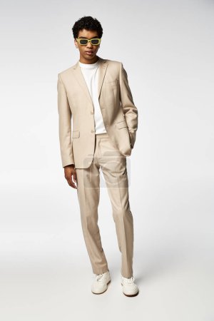 Handsome model sporting a beige suit and trendy sunglasses.