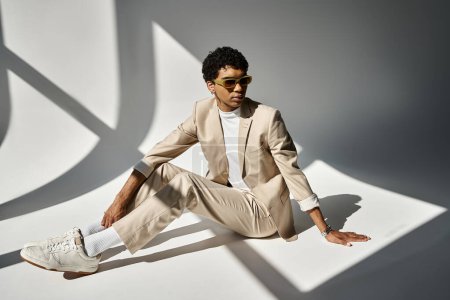 Afroamerikaner im braunen Anzug sitzt auf dem Boden und trägt Sonnenbrille.