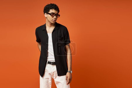 Schöner afroamerikanischer Mann mit stylischer Sonnenbrille, bekleidet mit schwarzem Hemd und weißer Hose.