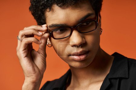 Photo for Handsome young man in glasses striking a pose against an orange backdrop - Royalty Free Image