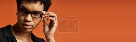 Téléchargez les photos : Un jeune homme élégant portant des lunettes sur un fond orange vif. - en image libre de droit