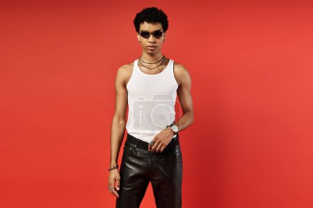 Handsome African American man wearing leather pants and a white tank top, exuding confidence and style.