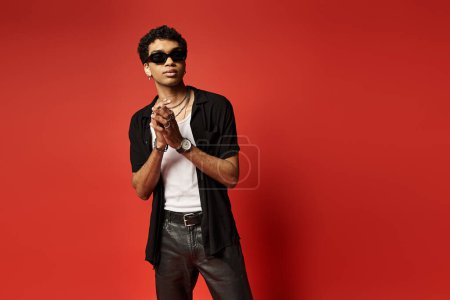 Schöner afroamerikanischer Mann mit Sonnenbrille posiert vor leuchtend rotem Hintergrund.