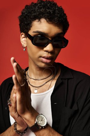 Foto de Joven hombre afroamericano en camisa negra con gafas de sol con confianza. - Imagen libre de derechos