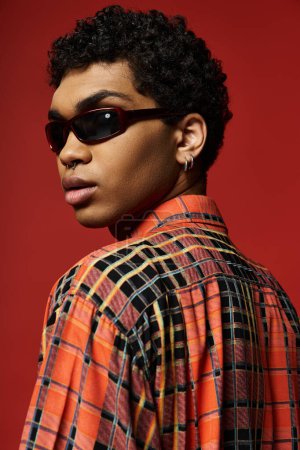 Foto de Young man looking stylish in sunglasses and a plaid shirt. - Imagen libre de derechos