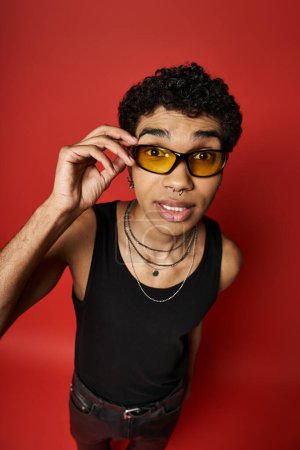 Afroamerikaner mit stylischer Sonnenbrille auf leuchtend rotem Hintergrund.
