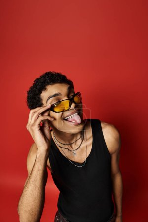 Hombre afroamericano guapo con gafas de sol, sacando su lengua juguetonamente.
