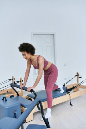 Mujer activa en top rosa y polainas corriendo en cinta de correr.