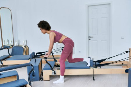 Woman in pink top exercises on rowing machine.