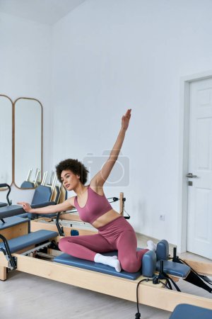 Una mujer con un top rosa y pantalones rosados está realizando ejercicios con gracia.