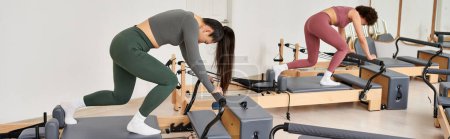 Two women confidently stand atop exercise equipment.