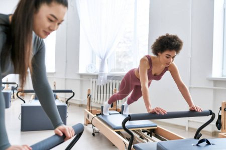 Attractive woman is intensively exercising next to her friend.