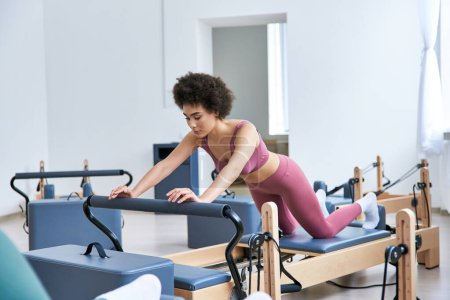 Eine Frau im rosafarbenen Top trainiert in einem Fitnessstudio.