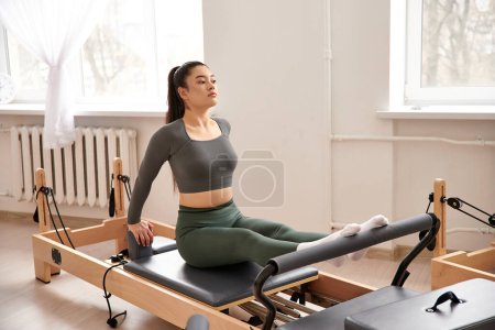 Woman in gray top and green pants gracefully exercising.