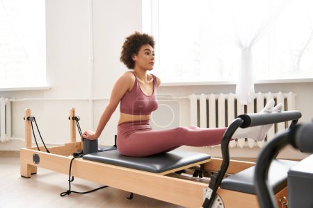 Jeune femme afro-américaine en haut de soutien-gorge de sport rose et leggings exercice.