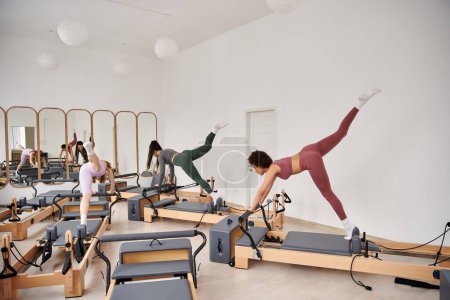 Sporty women performing exercises during a Pilates lesson in a gym.