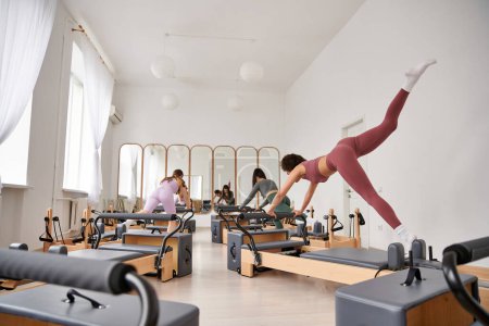 Beautiful women engage in a Pilates session in a gym.