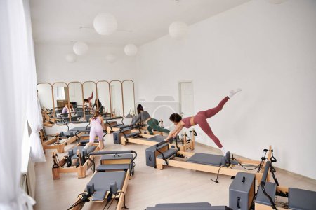Appealing women engage in a Pilates session in a gym.