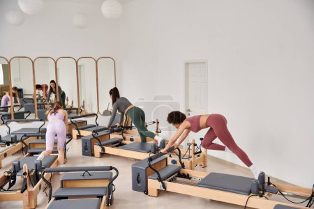 A group of sporty women engaging in a pilates workout at the gym.