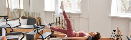 A pretty, sporty woman exercises in a gym during a pilates lesson.
