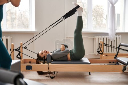 A sporty woman demonstrates grace and strength as she executes a pivot during a pilates lesson.