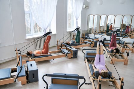 Frauengruppe, die im Fitnessstudio verschiedene Übungen macht, insbesondere Pilates.